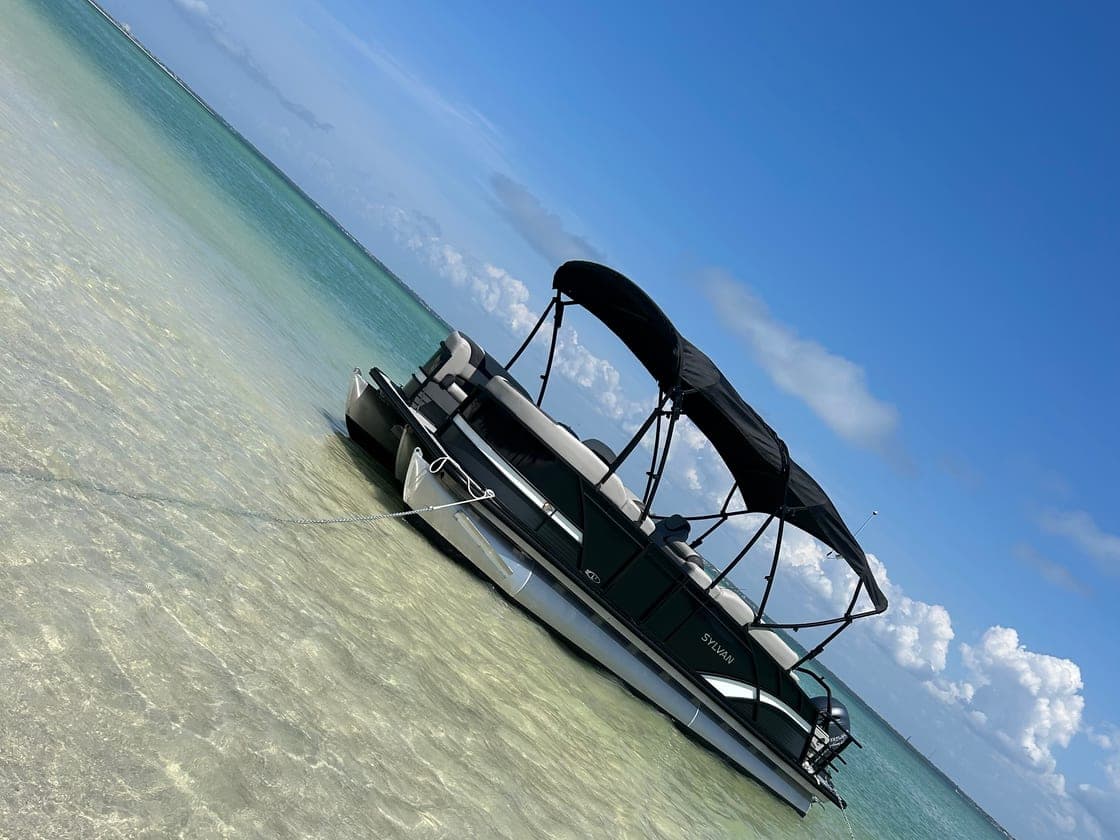 Pontoon boat anchored at a shallow Clearwater Beach sandbar with people swimming